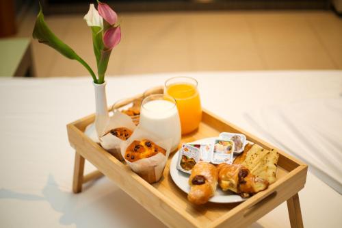 a tray with a plate of food and a vase with a flower at Aliko Hotel in Vlorë