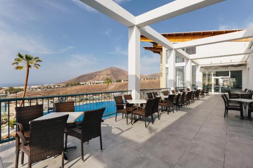 a patio with tables and chairs and a view of the ocean at Alua Village Fuerteventura - All Inclusive in Playa Jandia