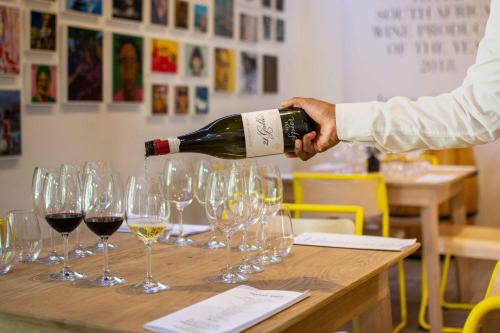 a person pouring wine into wine glasses on a table at Indaba Hotel, Spa & Conference Center in Johannesburg