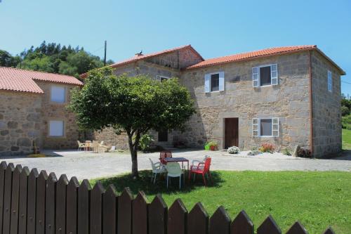 una casa in pietra con tavolo e sedie in cortile di Albergue Rectoral San Mamede da Pena EXCLUSIVE FOR PILGRIMS a Negreira