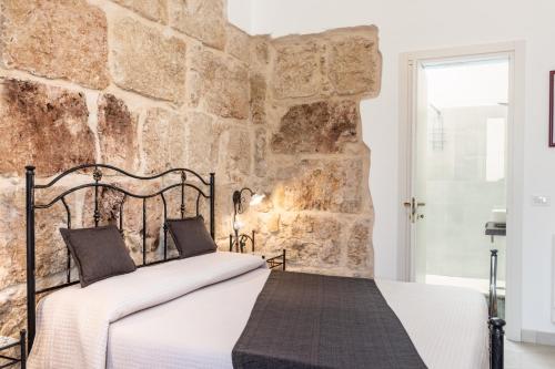 a bed in a room with a stone wall at Morfeo Charming Rooms & Relax in Avola