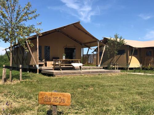 a sign in the grass in front of a house at De Hazelaarshof Luxe glampingtent bij natuurgebied De Millingerwaard in Kekerdom