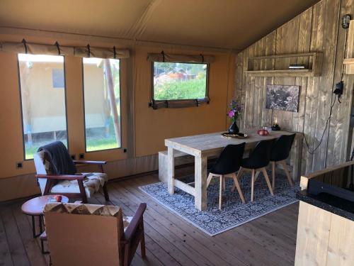 a living room with a wooden table and chairs at De Hazelaarshof Luxe glampingtent bij natuurgebied De Millingerwaard in Kekerdom