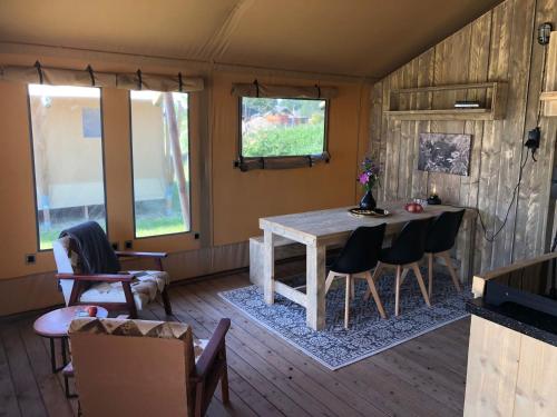 een woonkamer met een houten tafel en stoelen bij De Hazelaarshof Luxe glampingtent bij natuurgebied De Millingerwaard in Kekerdom