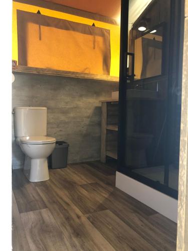 a bathroom with a toilet and a wooden floor at De Hazelaarshof Luxe glampingtent bij natuurgebied De Millingerwaard in Kekerdom