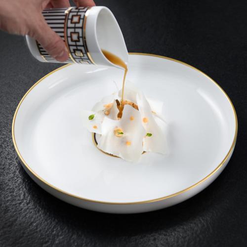 a person is pouring food onto a white plate at Laqua Vineyard in Terricciola