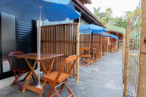 a row of tables and chairs with blue umbrellas at Residencial Solar do Pescador in São Sebastião