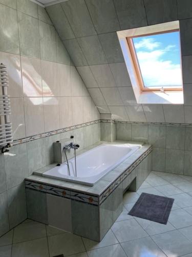 a bathroom with a bath tub with a window at Pokoje Alicja in Łeba