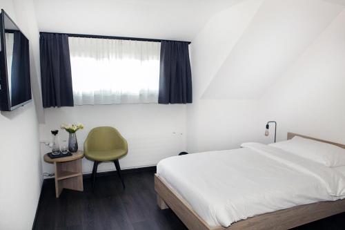 ein Schlafzimmer mit einem Bett, einem Stuhl und einem Fenster in der Unterkunft Dihei - Hotel, Lounge, Bar in Dübendorf