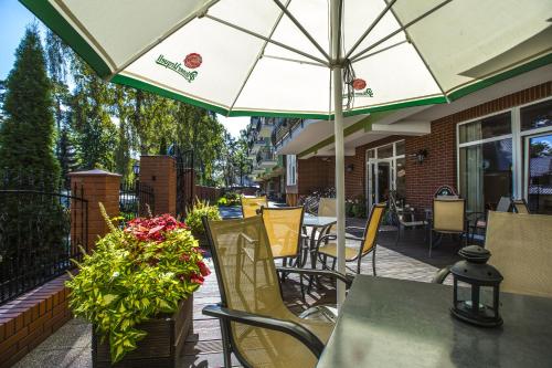 a patio with a table and chairs and an umbrella at Maximus Spa in Dziwnówek