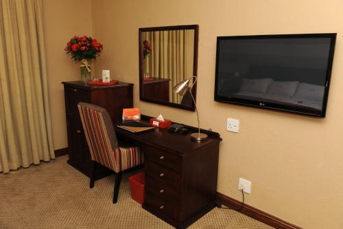 a hotel room with a desk and a television on the wall at Indaba Hotel, Spa & Conference Center in Johannesburg