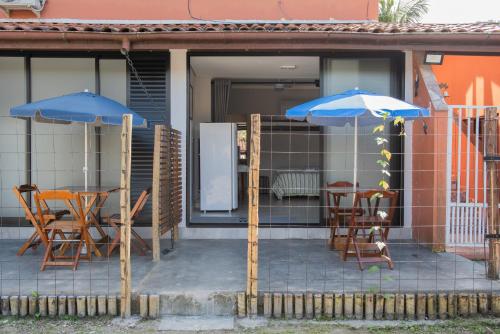 a patio with two blue umbrellas and tables and chairs at Residencial Solar do Pescador in São Sebastião