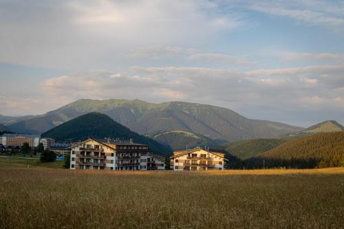 a building in a field with mountains in the background at Panorama apartmán 44-C in Donovaly