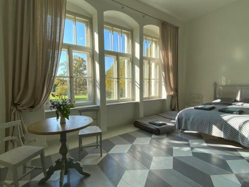 a bedroom with a bed and a table and windows at Oleru muiža 
