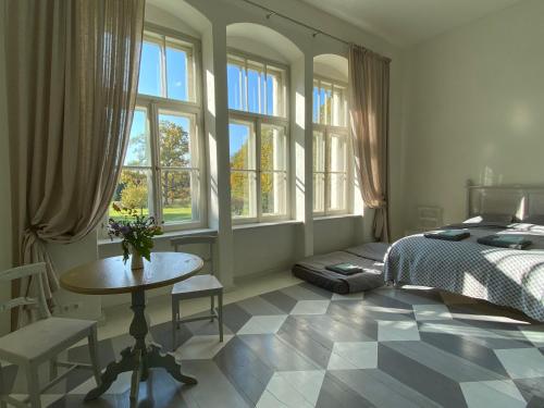 a bedroom with a bed and a table and windows at Oleru muiža in Oleri