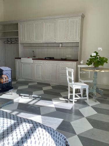 a kitchen with white cabinets and a table and a chair at Oleru muiža in Oleri
