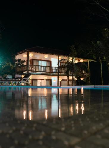 a house at night with a pool in front of it at Pousada Recanto Caxando in Trancoso