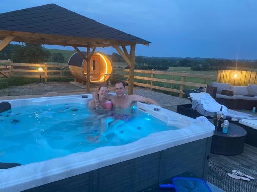 Un uomo e una ragazza seduti in una vasca idromassaggio di Country House and Spa a Coleraine