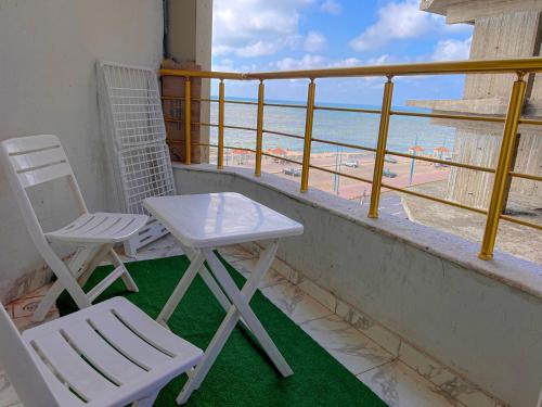 2 Stühle und ein Tisch auf dem Balkon mit Blick auf den Strand in der Unterkunft SPACIOUS 3BED APT BEACH FRONT VIEW OF ALEXANDRIA in Alexandria