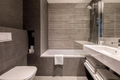 a bathroom with a tub and a toilet and a sink at Chalet Hôtel Le Prieuré & Spa in Chamonix-Mont-Blanc