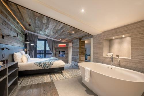 a bedroom with a bed and a tub in a room at Chalet Hôtel Le Prieuré & Spa in Chamonix-Mont-Blanc