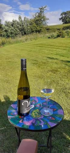 a bottle of wine sitting on a table with a glass at Meadowsweet @ Laneside in Whitby
