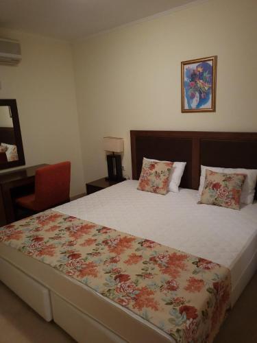 a bedroom with a large bed with a flower blanket at Апартамент Сънсет Ризорт in Pomorie