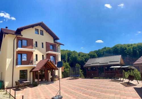 a large building with a brick patio in front of it at Pensiunea 7 Brazi II in Poiana Mărului