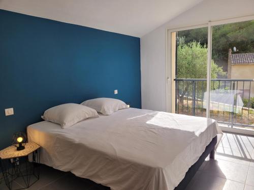 a blue bedroom with a bed and a large window at L'Oustau de Laëtitia Animaux bienvenus in Fontaine-de-Vaucluse