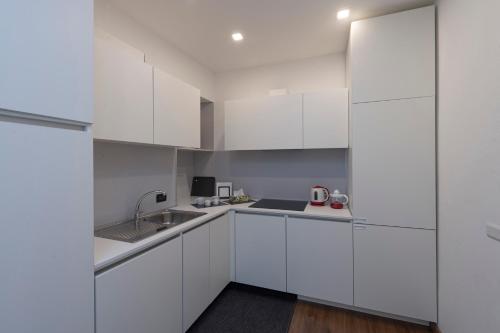 a white kitchen with white cabinets and a sink at Casa David in Stresa