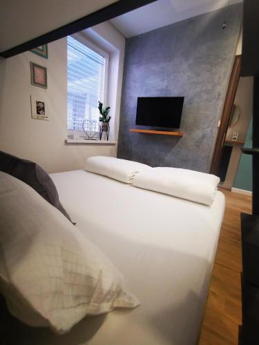 a bedroom with a large white bed with a tv on the wall at Apartment Keleia in Celje