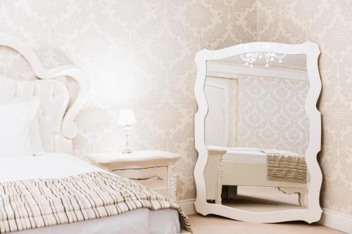 a bedroom with a white bed and a mirror at Hotel Dukagjini in Peje