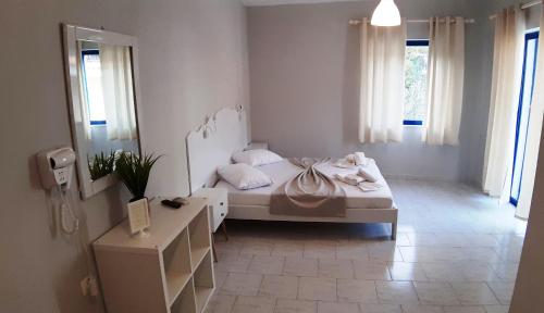 ein weißes Schlafzimmer mit einem Bett und einem Spiegel in der Unterkunft blue & white askeli studios in Poros