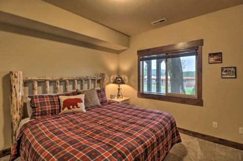 a bedroom with a bed with a plaid blanket and a window at Walkable Bigfork Townhome Fish, Hike and Ski! in Bigfork