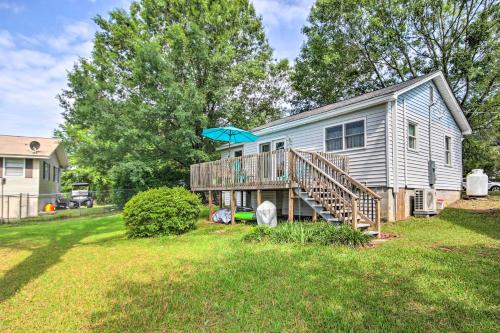 a house with a deck with an umbrella on it at Adorable Lakefront Cottage with Dock and Grill! in Lake Murray Shores
