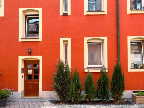 un edificio rojo con árboles delante de él en Nurban Apartments City Nürnberg, en Núremberg