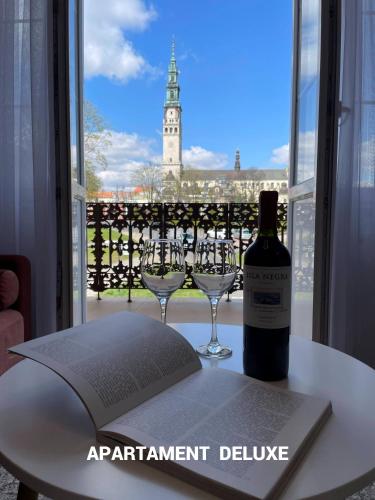 a bottle of wine sitting on a table with two glasses at Biały Kruk Apartamenty vis-a-vis Jasnej Góry in Częstochowa