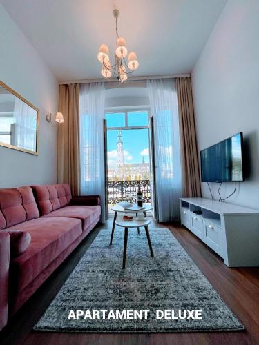 a living room with a pink couch and a tv at Biały Kruk Apartamenty vis-a-vis Jasnej Góry in Częstochowa
