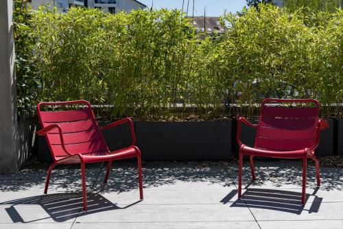 two red chairs sitting next to each other on a sidewalk at Le Kube - Appartements de Prestige au centre d'Annecy in Annecy