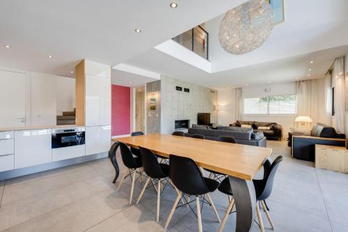a kitchen and living room with a wooden table and chairs at Le Kube - Appartements de Prestige au centre d'Annecy in Annecy