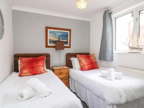 1 dormitorio con 2 camas y almohadas rojas en Sea Breeze en Weymouth