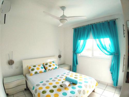 a bedroom with a bed with blue curtains and a window at My sweet home in Paphos City