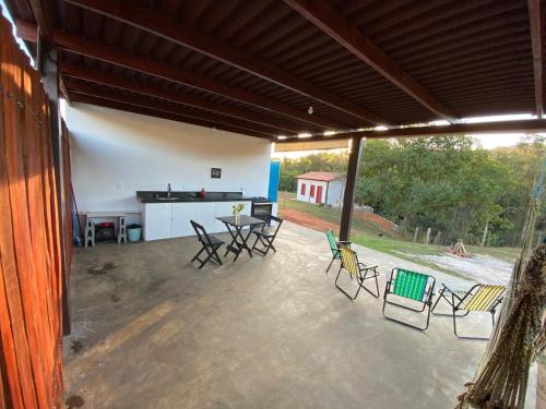 eine Terrasse mit Stühlen, einem Tisch und einem Grill in der Unterkunft Espaço Tropicália in Pirenópolis