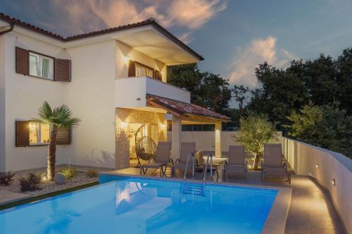 a villa with a swimming pool in front of a house at Villa AntoNada in Krk