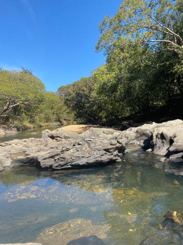 a river with rocks and trees in the background at Espaço Tropicália in Pirenópolis
