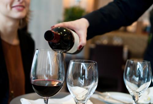 a person pouring wine into two wine glasses at Best Western Plus Paris Saclay in Saclay