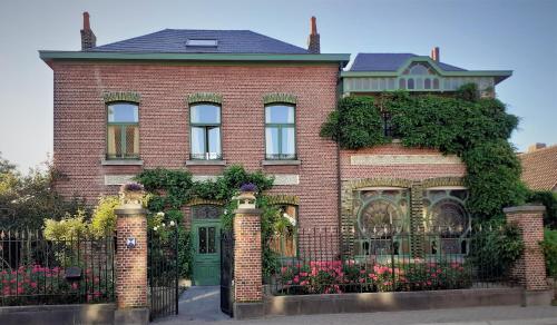 une maison en briques rouges avec un portail et des fleurs dans l'établissement Villa Ritte, à Termonde