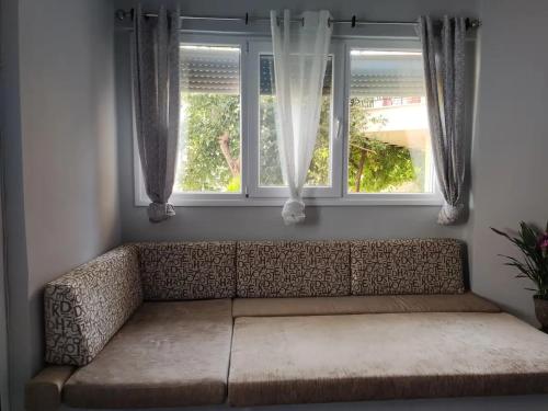 a couch in a room with two windows at Μοντέρνο Studio στην πόλη Καβάλα(1,5 χμ από ακτή) in Kavala