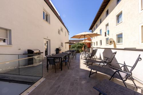 an outdoor patio with tables and chairs and an umbrella at Luxury Apartment Monte Carlo in Pörtschach am Wörthersee