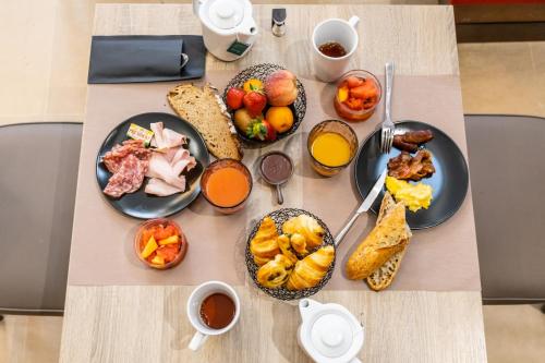 a table with plates of breakfast food on it at Hotel De Bourbon Grand Hotel Mercure Bourges in Bourges